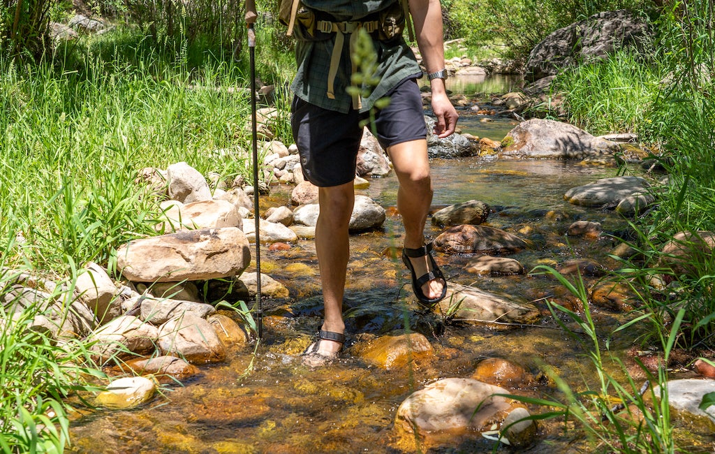 thru-hiker atravesando un río con sandalias minimalistas