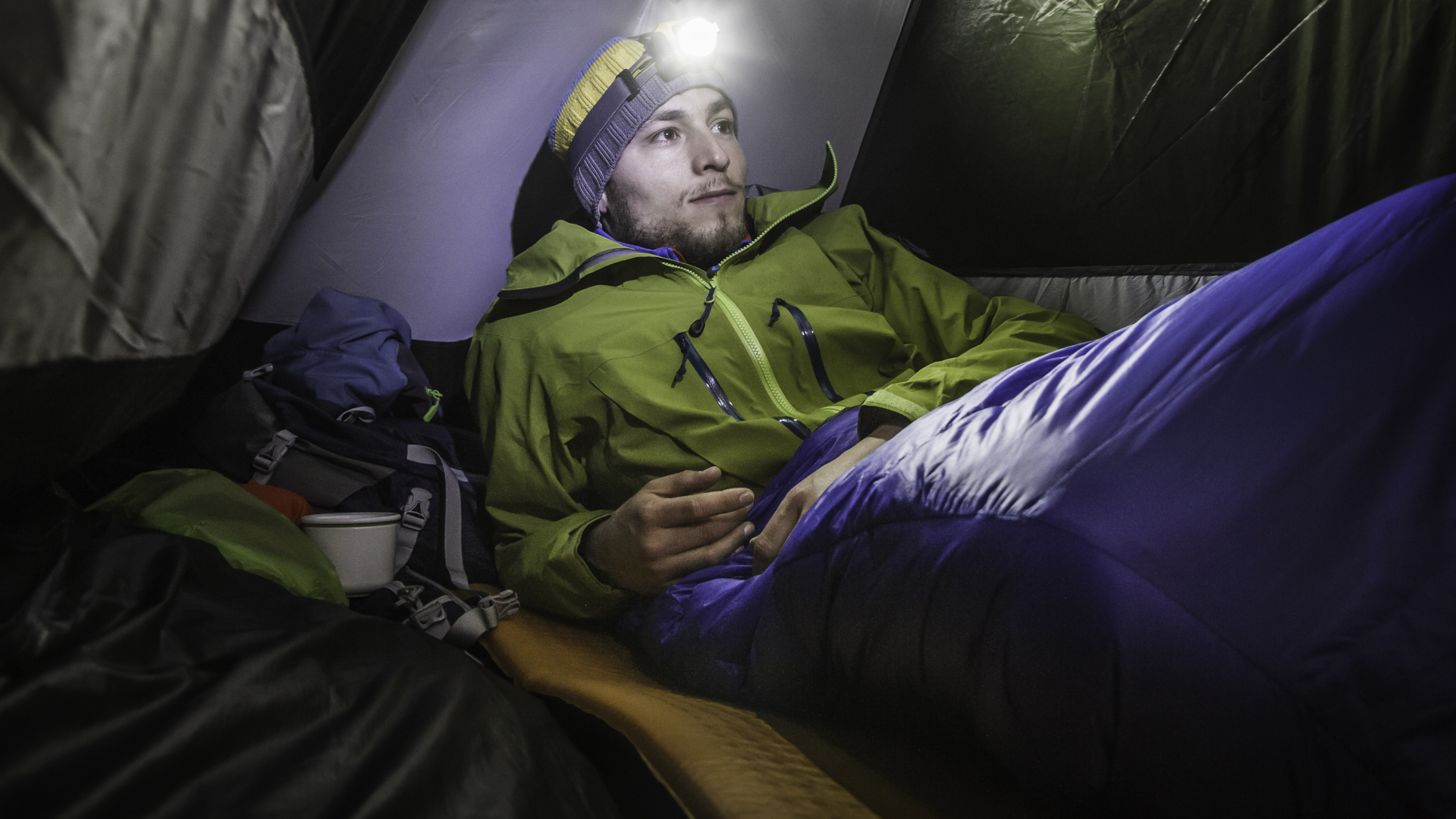 Cómo acampar bajo la lluvia: un hombre dentro de su saco de dormir en su tienda