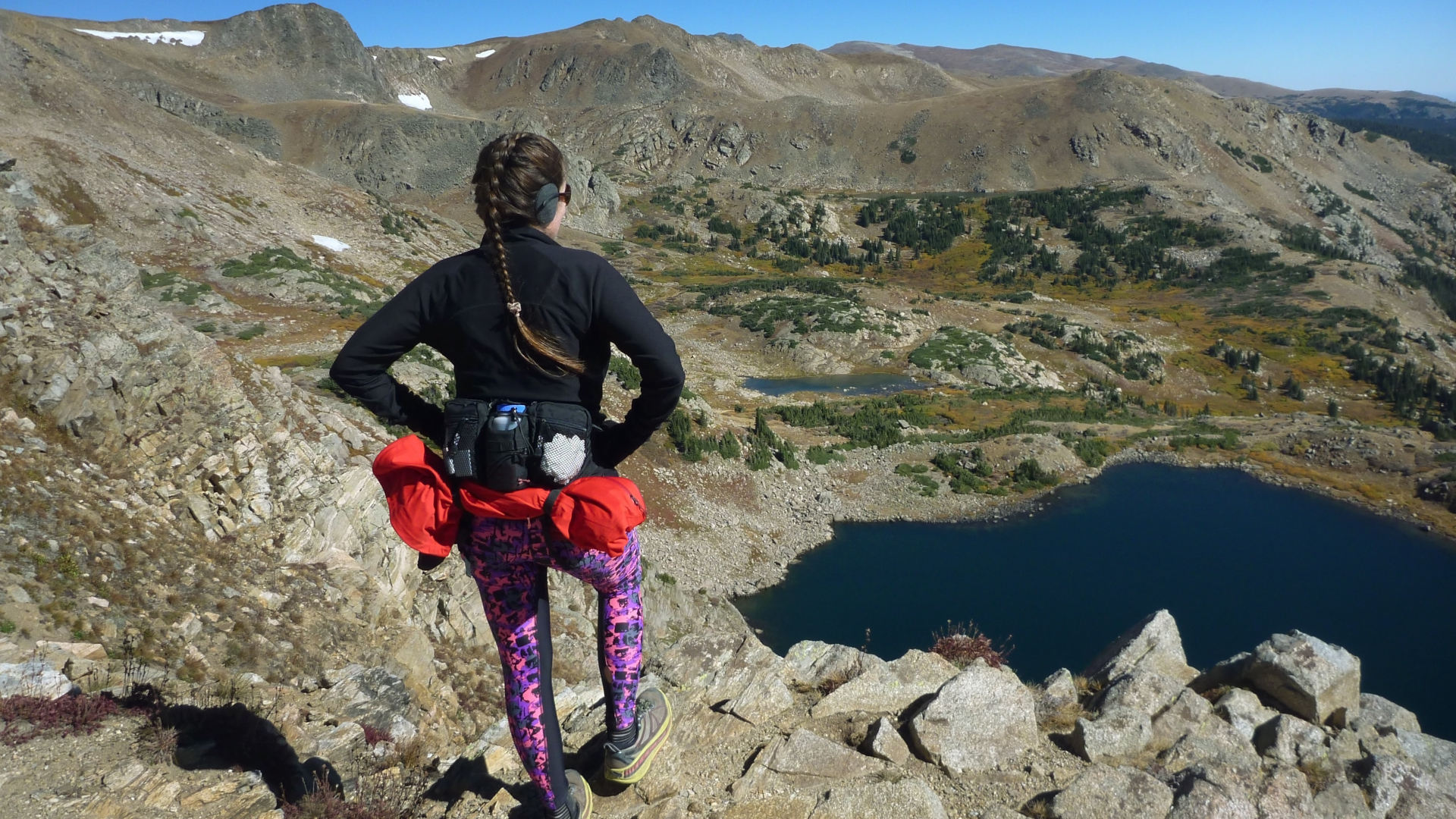 Un excursionista con una riñonera mira hacia un lago alpino en las Montañas Rocosas