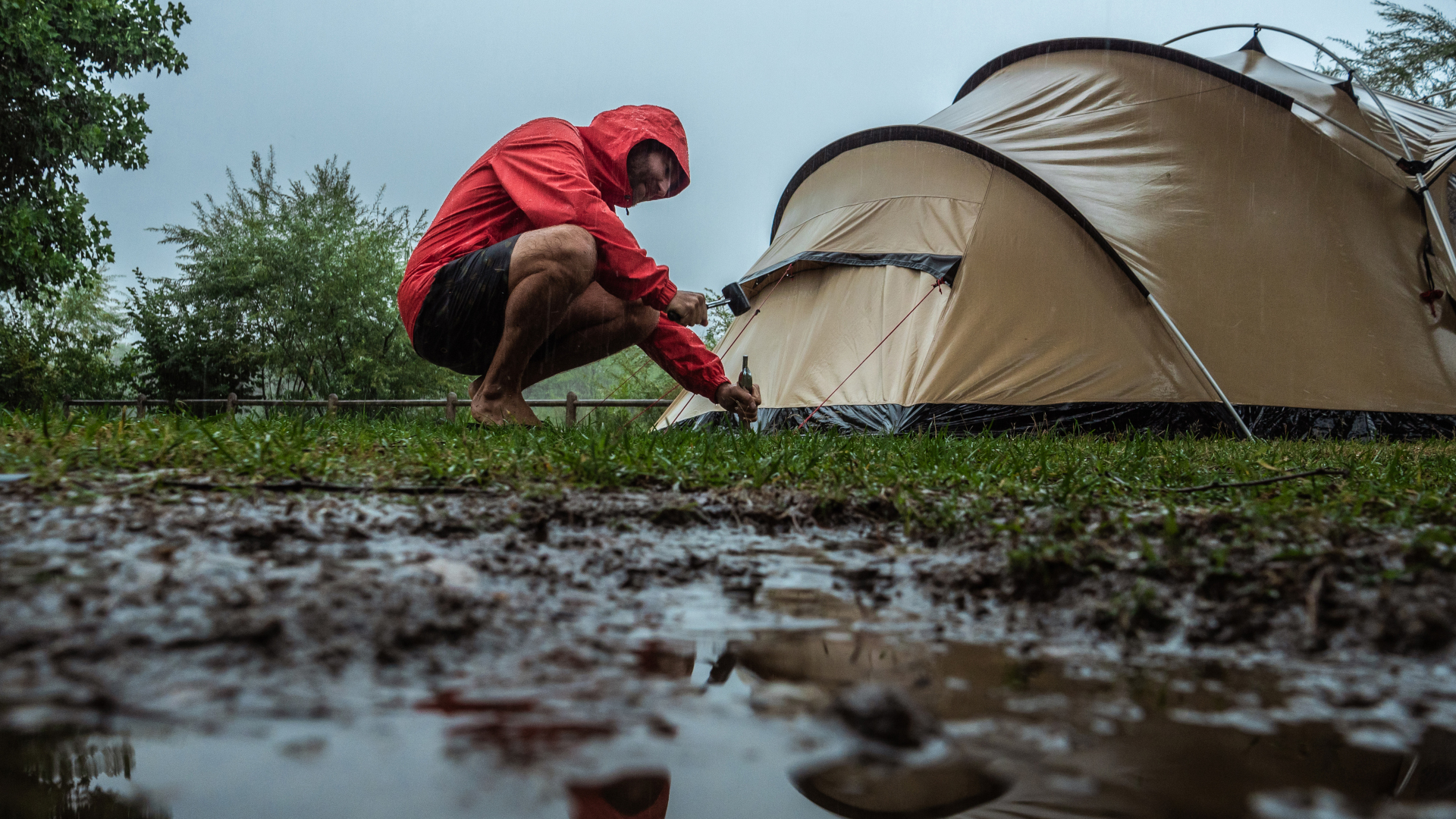 cómo acampar bajo la lluvia: un hombre instalando su tienda bajo la lluvia