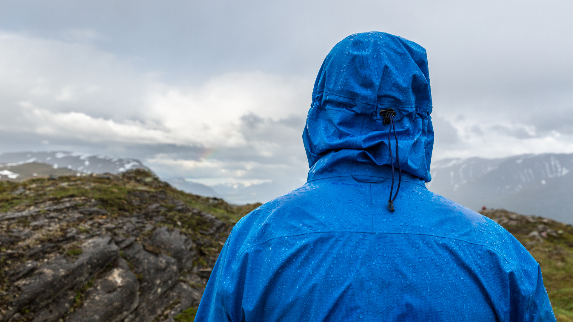 Una persona con una chaqueta impermeable mirando al horizonte.
