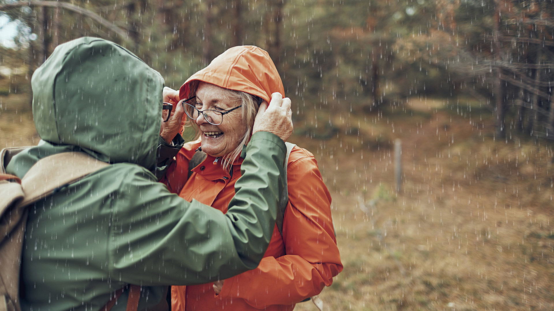 Una excursionista ajusta la capucha de sus compañeros mientras caminan bajo la lluvia.