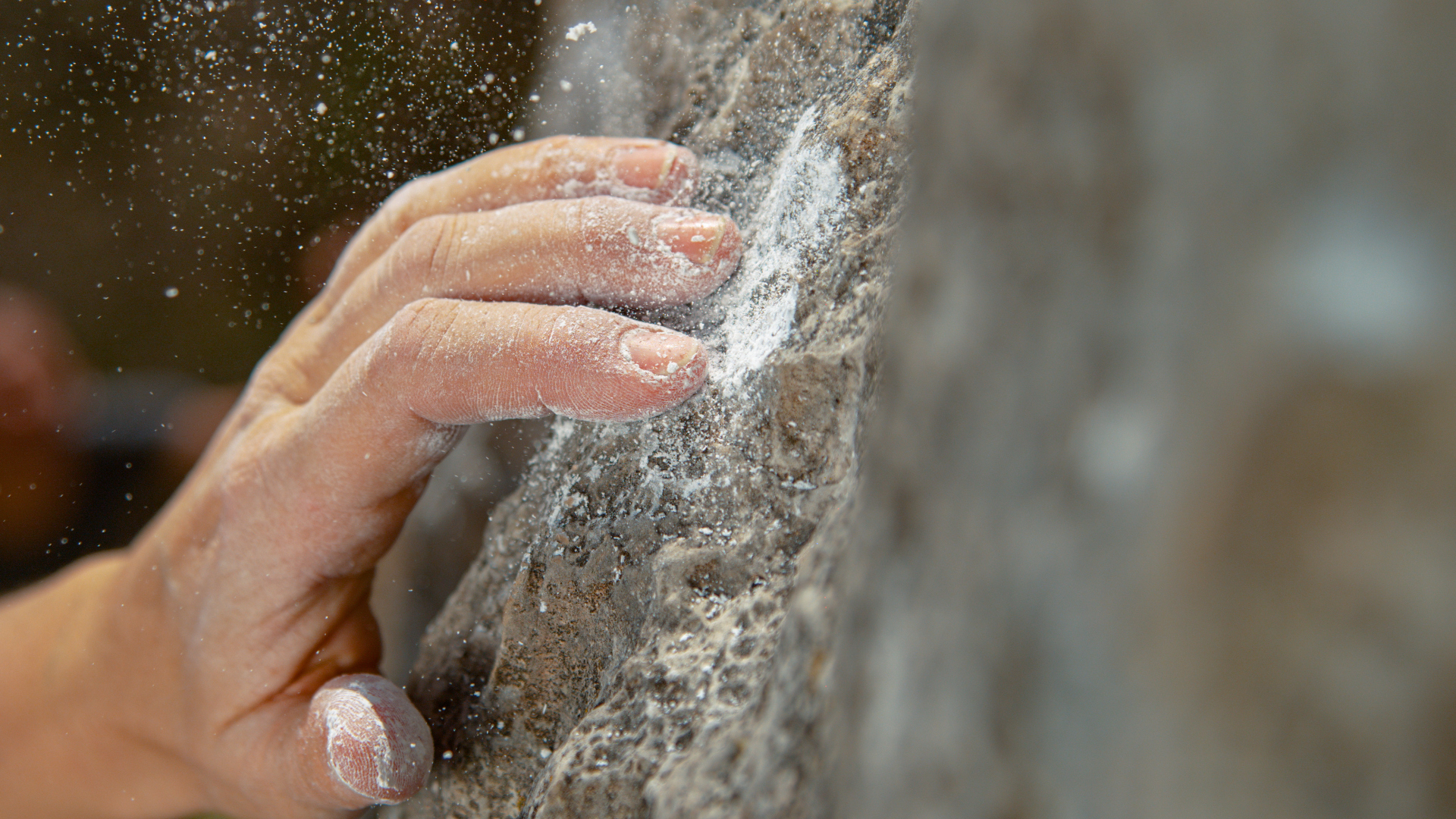 Un primer plano de la mano de un escalador mientras se desliza de la roca