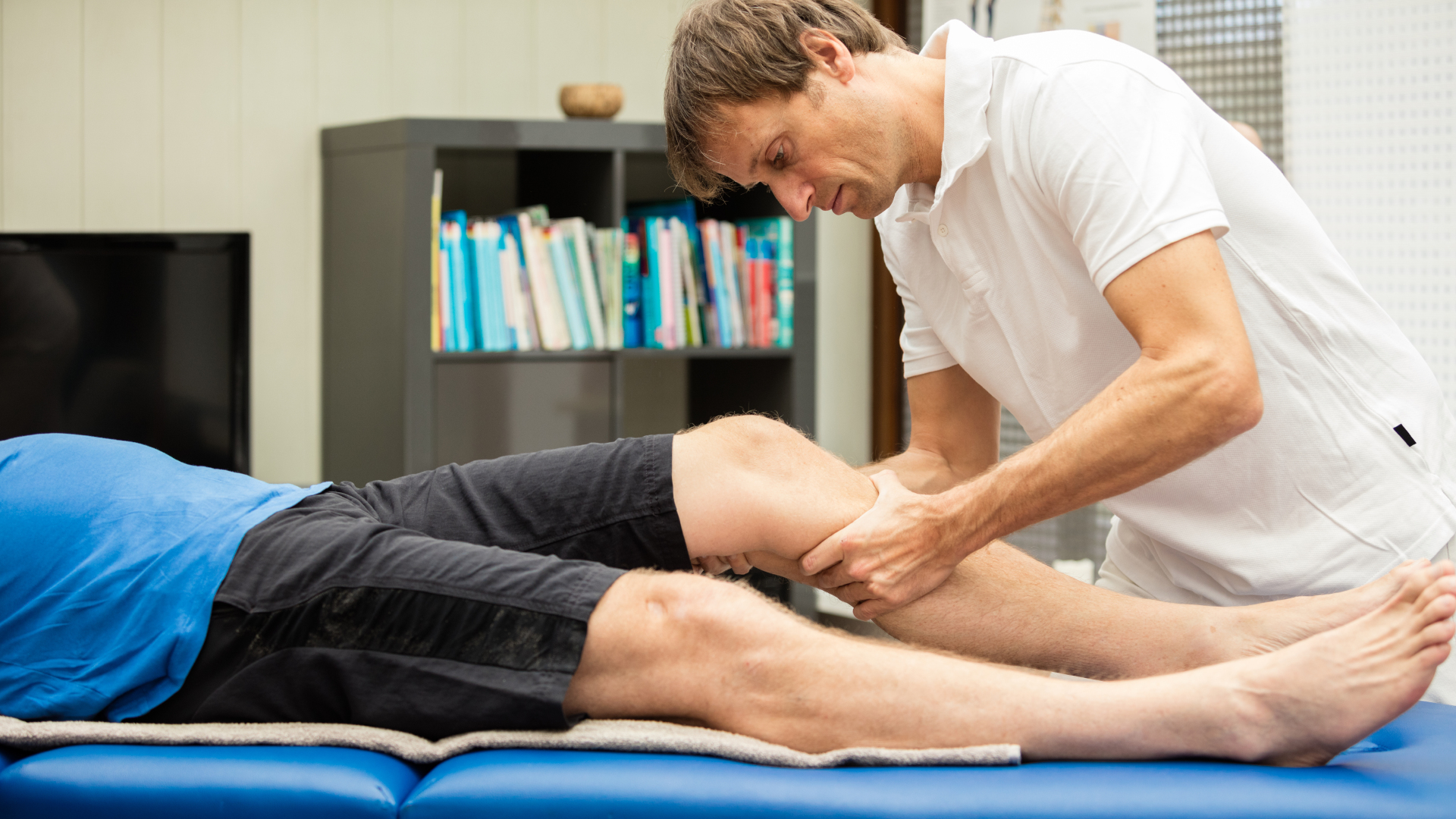 Un hombre dando un masaje deportivo a los músculos de la pantorrilla de un atleta