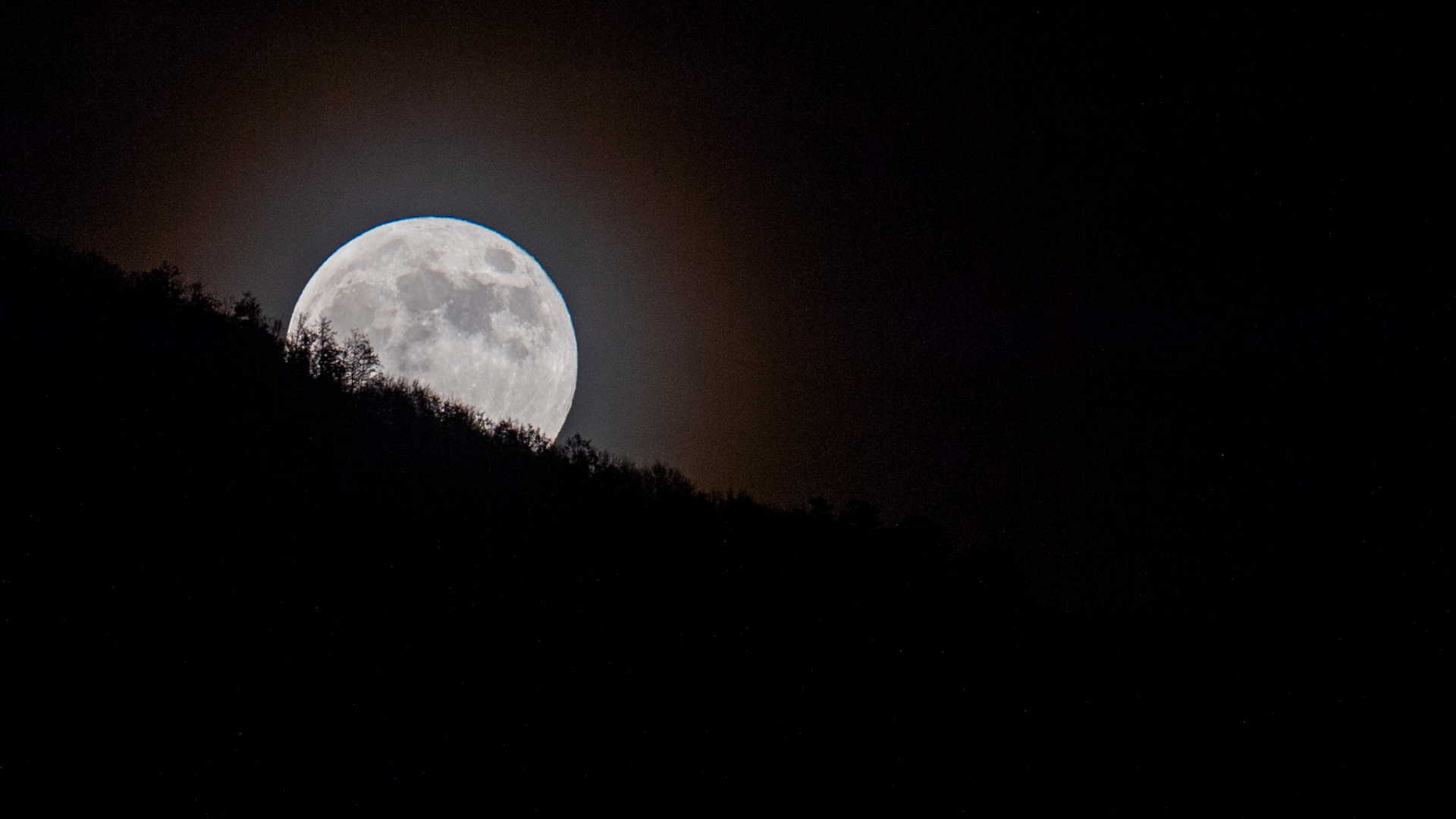 La luna llena alcanza su punto máximo sobre la montaña.