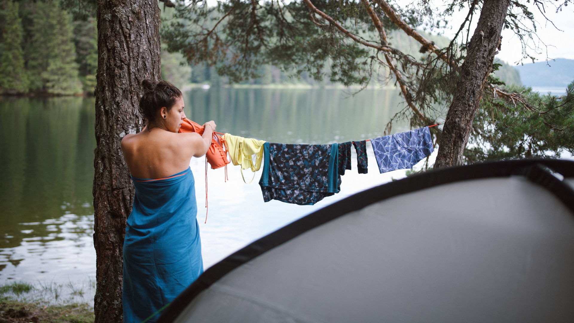 Cómo acampar bajo la lluvia: una mujer cuelga su ropa para que se seque en el campamento