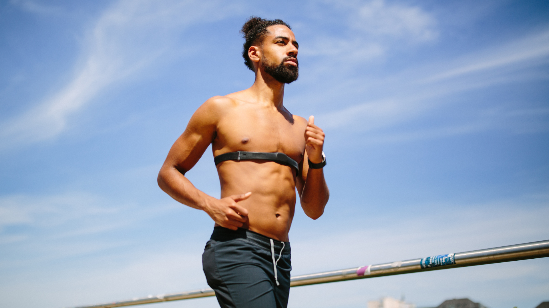 Un corredor con el torso desnudo que usa un monitor de frecuencia cardíaca con correa para el pecho