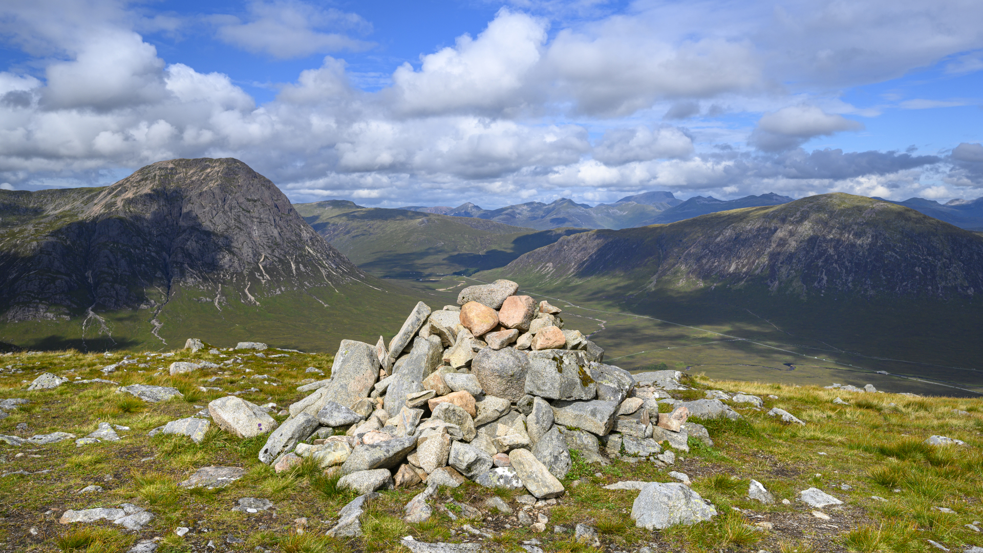 Un mojón de rocas en una montaña con colinas al fondo