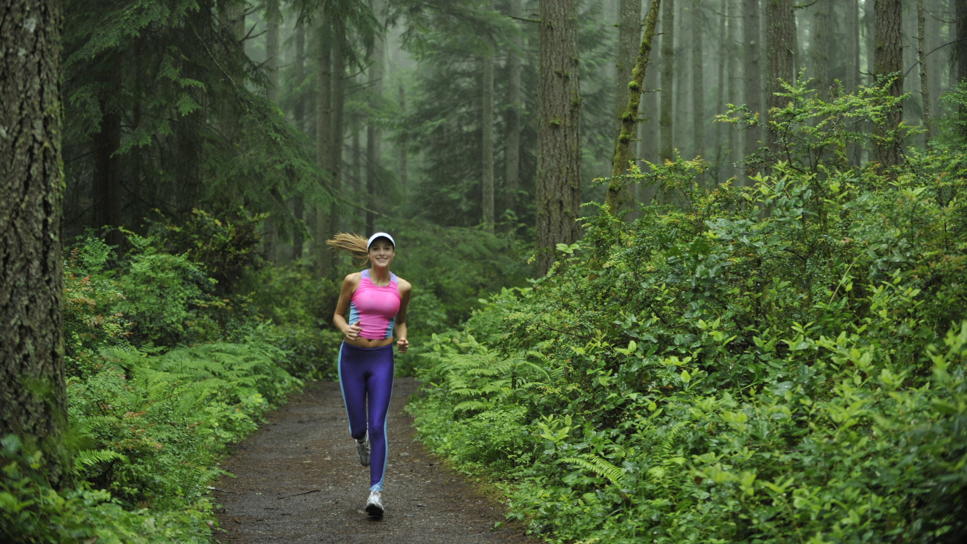 Una mujer corriendo por un sendero boscoso