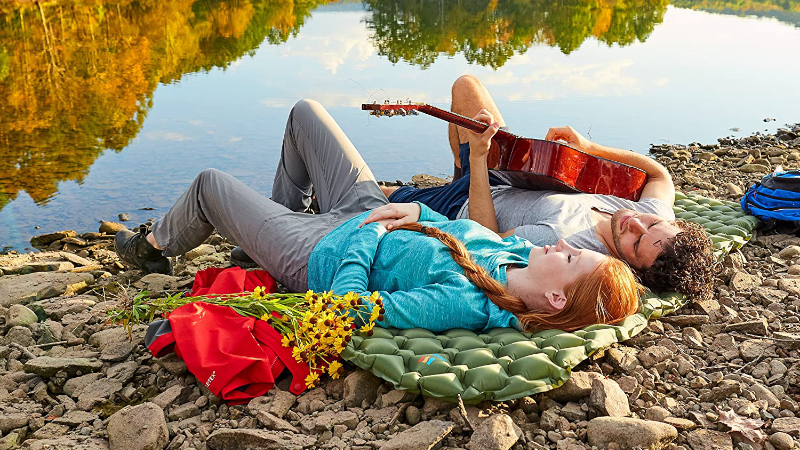 colchoneta de dormir vs colchón de aire: pareja con una guitarra cantando en una colchoneta de dormir