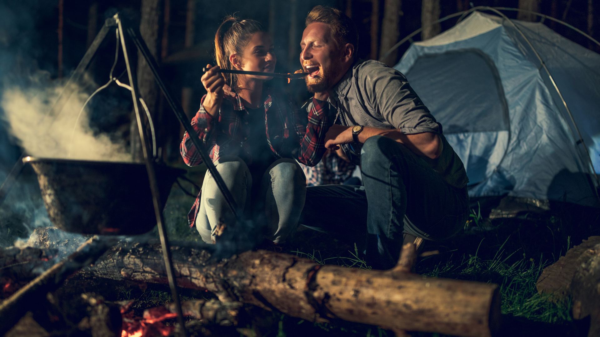 Una pareja comiendo una comida que cocinaron en un horno holandés para acampar