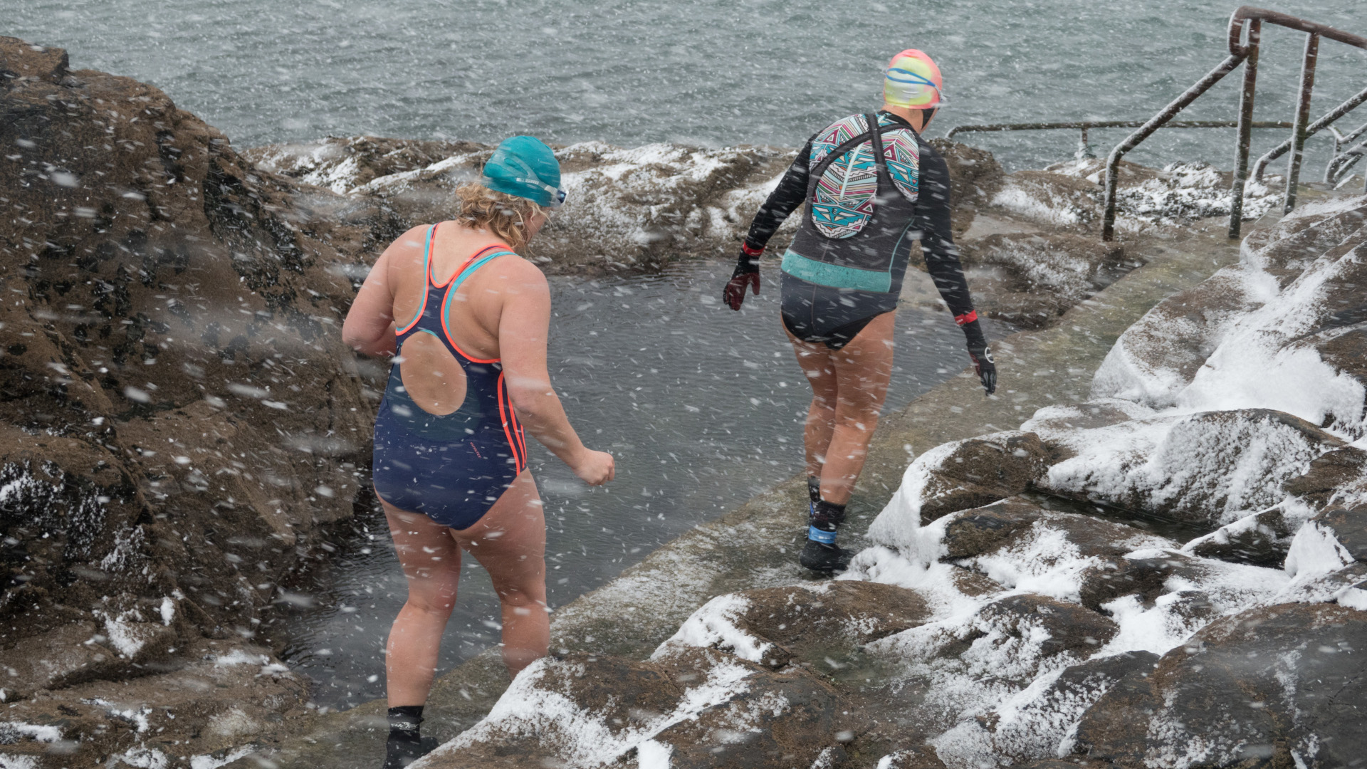 Dos mujeres preparándose para nadar salvajemente en un día de nieve