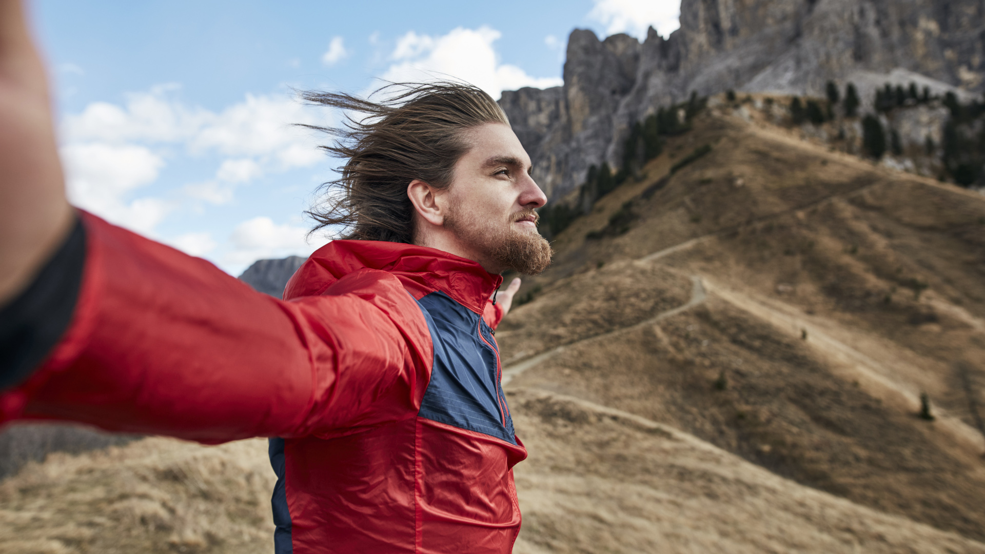 Un excursionista se inclina hacia el viento con los brazos abiertos.