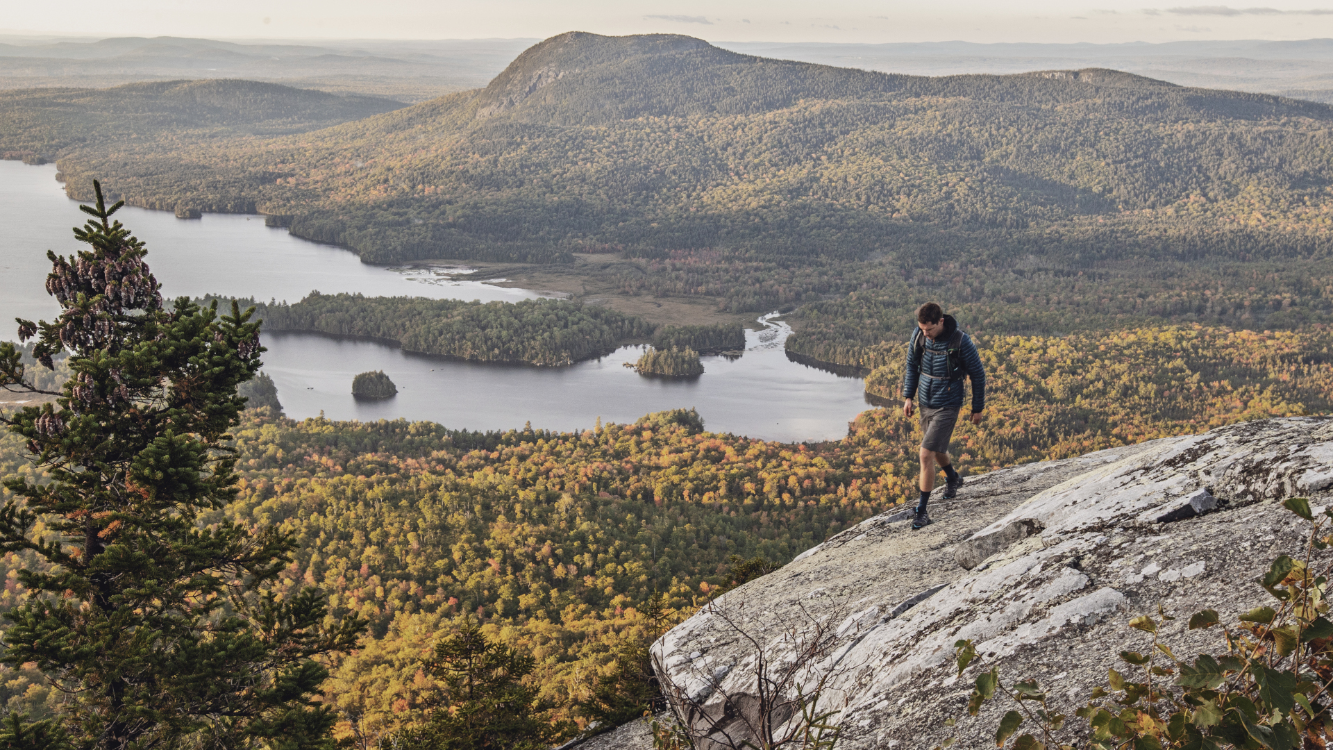 Un excursionista cruza una cumbre rocosa sobre un lago en el sendero de los Apalaches en Maine