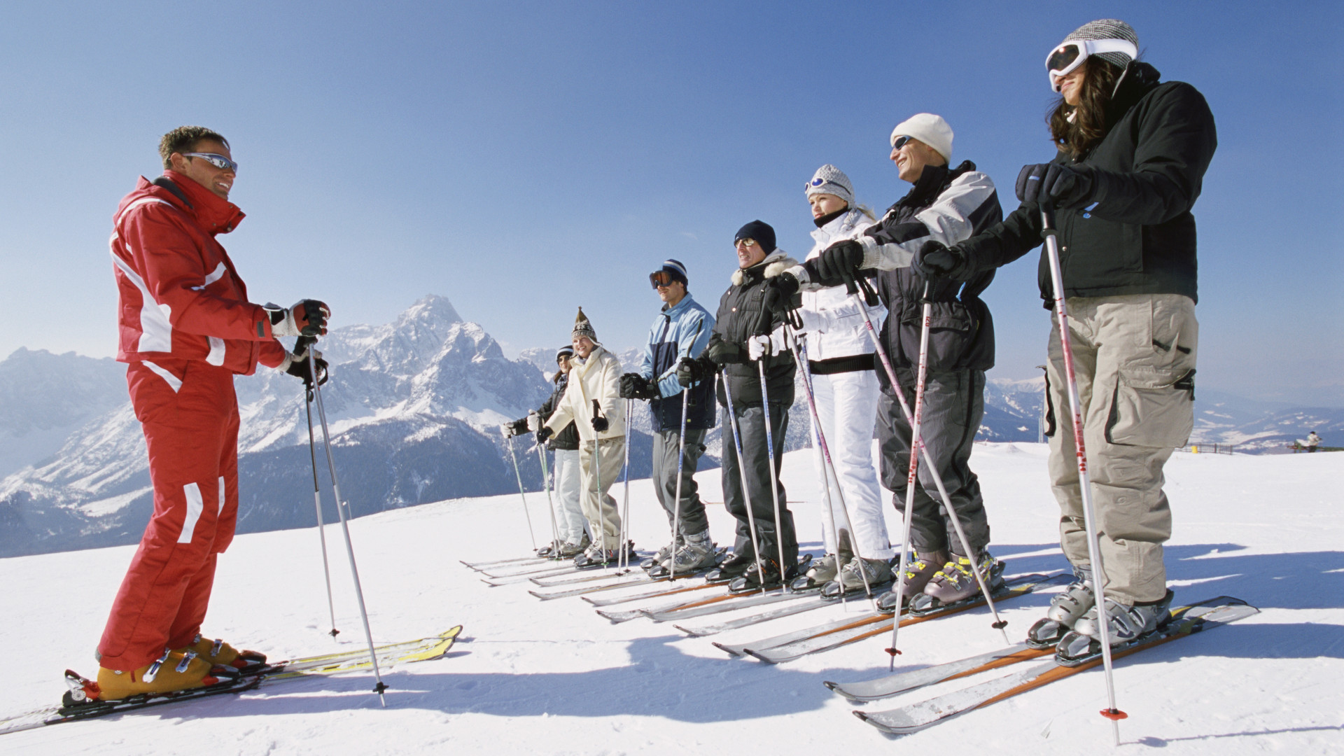 Un grupo tomando una lección de esquí con un instructor.
